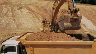 Una excavadora carga un camión en la faena (ejemplo)